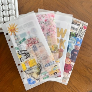 May include: A collection of New York-themed stickers in clear plastic sleeves. The stickers feature iconic city imagery, including a martini, Broadway signs, and a teddy bear. The text "NEW YORKER" and "I NY" are visible.