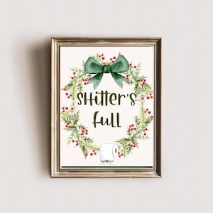 May include: A Christmas-themed bathroom sign with a green wreath and red berries. The sign reads "Shitter's Full".
