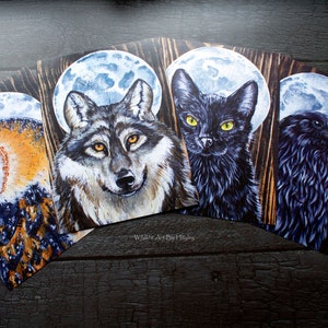 May include: Four wood-mounted prints featuring a wolf, a cat, an owl, and a raven, each with a full moon behind them. The prints are all in a dark, painterly style.