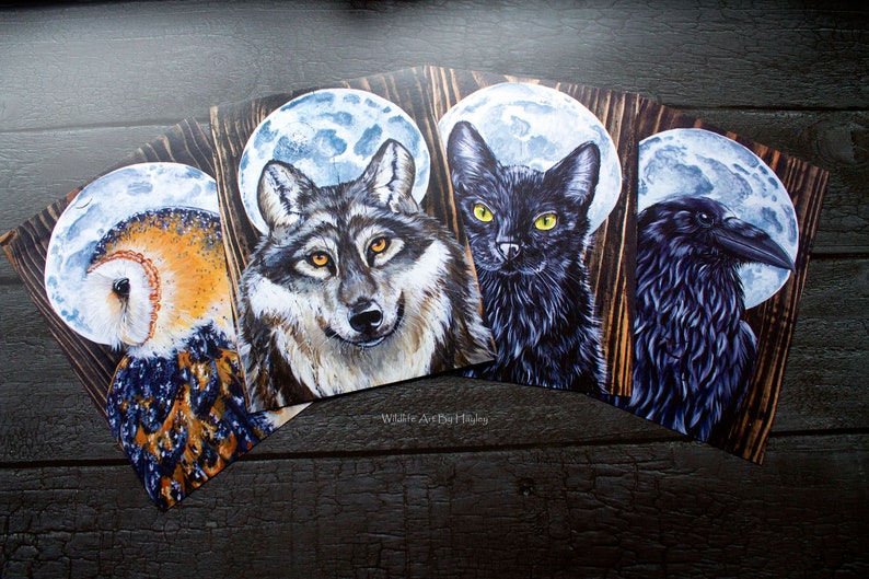 May include: Four wood-mounted prints featuring a wolf, a cat, an owl, and a raven, each with a full moon behind them. The prints are all in a dark, painterly style.