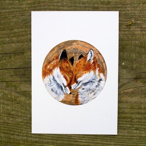 May include: A painting of two red foxes curled up together, sleeping. The foxes are painted in a realistic style on a round, wooden surface.