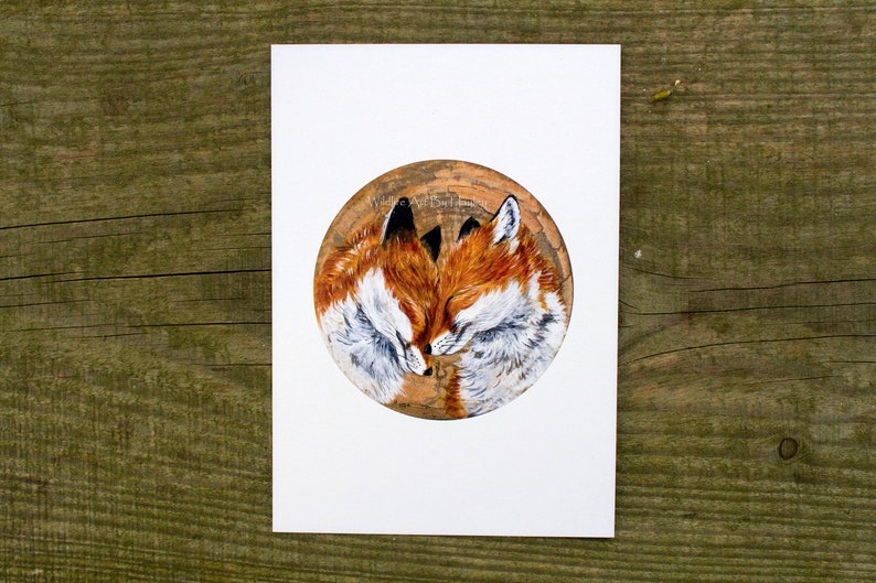 May include: A painting of two red foxes curled up together, sleeping. The foxes are painted in a realistic style on a round, wooden surface.