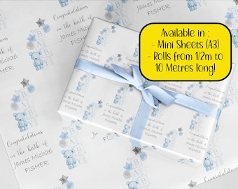 May include: Blue and gray baby shower wrapping paper with a teddy bear and blocks that spell out "BABY". The paper features the text "Congratulations on the birth of James Michael FISHER" repeated throughout. The text "Available in: Mini Sheets (A3) Rolls from 1/2m to 10 Metres long!" is also included.