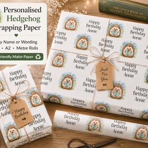 Könnte beinhalten: Personalisiertes Geschenkpapier mit einem sich wiederholenden Muster von Igeln, die Bücher lesen, mit dem Text "Happy Birthday Annie". Die verpackten Geschenke sind mit Bindfaden und einem Geschenkanhänger mit der Aufschrift "Just For You" gebunden.