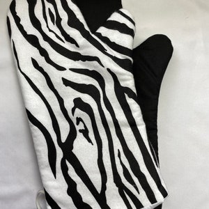 May include: Black and white zebra print oven mitt with a black heat-resistant lining. The mitt has a white trim and a white string tie.