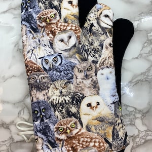 May include: A black oven mitt with a colourful owl print. The mitt is made of fabric and has a loop for hanging.