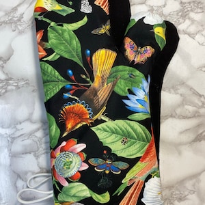 May include: Black oven mitt with a colorful floral and bird print. The print features birds, butterflies, flowers, and leaves on a black background.