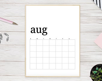 May include: A framed white calendar page for August with a grid for daily entries. The word "aug" is printed in a bold, black font at the top. The frame is a light wood color, and the background is a white wooden surface.