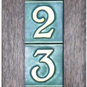 May include: A framed house number sign with the numbers 1, 2, 3, and 4 in white on a teal background.