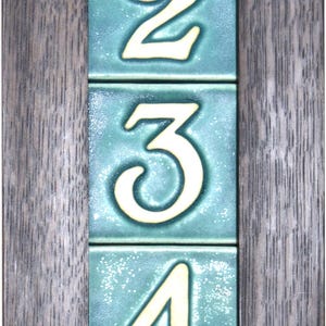 May include: A framed set of five ceramic tiles with the numbers 1 through 5 in white on a teal background.