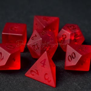 Peut inclure: Ensemble de sept dés translucides rouges avec des chiffres noirs. Les dés sont un d4, d6, d8, d10, d%, d12 et d20.