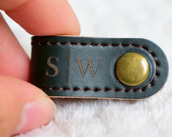 May include: A dark green leather strap with a brass button and the initials "S|W" engraved in the leather.