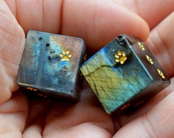 May include: Two iridescent blue, green, and gold dice with gold paw print designs on each side.