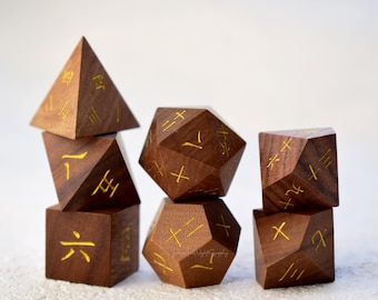 Könnte beinhalten: Satz von sechs Holzwürfeln mit goldenen Markierungen. Die Würfel haben verschiedene Formen, darunter eine Pyramide, ein Würfel und ein Dodekaeder. Die Würfel sind in einem Stapel angeordnet.