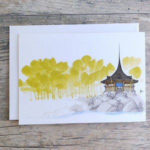May include: A watercolor painting of a small wooden structure with a pointed roof, surrounded by yellow trees and gray rocks. The structure has a blue door and windows, and a small path leads up to it.