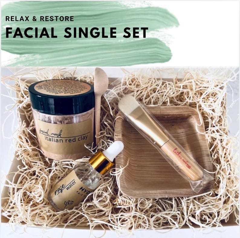 Puede incluir: Un set facial individual con un tarro de mascarilla facial de arcilla roja italiana, agua de rosas, una cuchara de madera, un cepillo y un plato cuadrado peque&ntilde;o. El set est&aacute; en una caja con paja y el texto "RELAX & RESTORE FACIAL SINGLE SET".