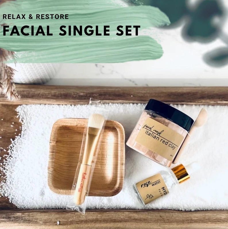 Puede incluir: Un juego facial individual con una bandeja de madera, un cuenco peque&ntilde;o de madera, un cepillo, un tarro de mascarilla facial de arcilla roja italiana y una botella de agua de rosas. El texto "Relax & Restore" y "Facial Single Set" son visibles.