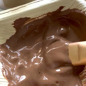 Puede incluir: Primer plano de una mascarilla facial marr&oacute;n, probablemente arcilla roja italiana, mezclada en un cuenco natural con forma de hoja. Se ve un peque&ntilde;o pincel, junto con un tarro etiquetado como "facial mask" y "Italian red clay".
