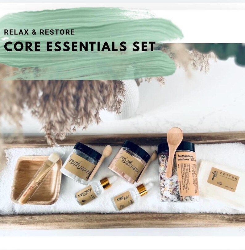 Puede incluir: Un juego Core Essentials con el texto "Relax & Restore". El juego incluye tarros de arcilla, aceites esenciales, un cepillo, una cuchara de madera y un pa&ntilde;o de algod&oacute;n. Los tarros tienen tapas y etiquetas negras.