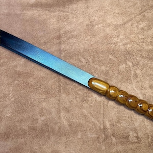 May include: A blue leather paddle with a wooden handle. The handle is made of multiple rounded pieces of wood.