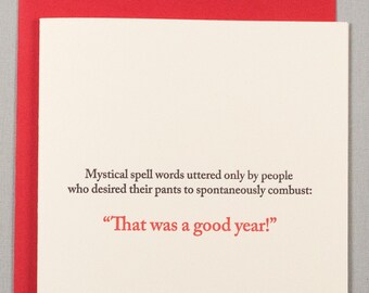 May include: A white card with a red envelope. The card has a humorous quote about the end of the year: "Mystical spell words uttered only by people who desired their pants to spontaneously combust: "That was a good year!"
