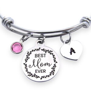 May include: Silver-tone expandable bracelet with three charms. One charm has a pink gemstone, another has the words "Best Mom Ever" in a wreath, and the third is a heart with the letter "A".