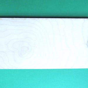 May include: A plain white wooden board with a natural wood grain pattern. The board has a small cutout on the right side.