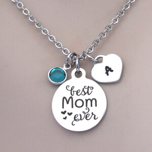May include: Silver necklace with a round pendant that says "best Mom ever" with two small hearts, a teal blue crystal charm, and a heart charm with the letter "A" engraved on it.