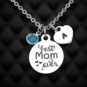 May include: Silver necklace with a round charm that says "best mom ever" with three small hearts, a teal blue crystal charm, and a heart charm with the letter "A" engraved on it.