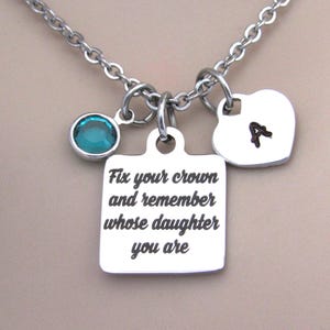 May include: Silver necklace with a square charm that reads "Fix your crown and remember whose daughter you are", a heart charm with the letter "A" engraved on it, and a teal blue gemstone.