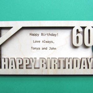 May include: A wooden card with a cutout design that says "Happy Birthday!" and "60" in large numbers. The card also has the text "Love Always, Tonya and John" inside the cutout.