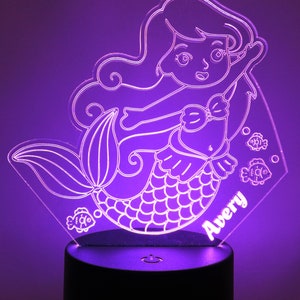 May include: A purple mermaid night light with a white outline and the name Avery. The light is on a black base with an on/off switch.