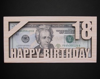 May include: A wooden frame with the number 18 cut out, and the words "HAPPY BIRTHDAY" cut out below. The frame holds a twenty-dollar bill. The background is black.