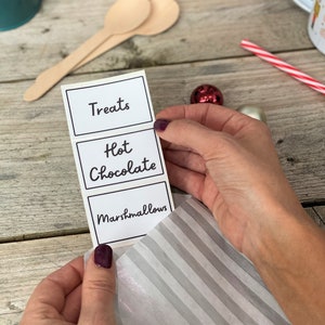 Peut inclure: Trois &eacute;tiquettes blanches avec du texte noir. Les &eacute;tiquettes indiquent "Treats", "Hot Chocolate" et "Marshmallows".