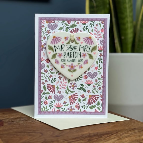 A lilac folksy wedding card that ships with an actual ceramic heart keepsake — you're gifting two objects in one envelope.