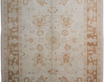 May include: A beige rug with a brown geometric pattern. The rug has a central medallion with a floral design. The rug is made of wool and is in good condition.