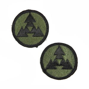 May include: Two green and black embroidered patches with a triangular design. The patches feature three black triangles with a smaller triangle in the center.