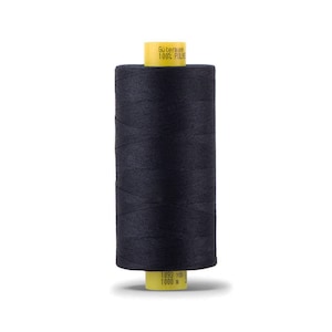 May include: A spool of black thread with a yellow label that reads " Gütermann 100% Polyester 1093 yds 1000 m "