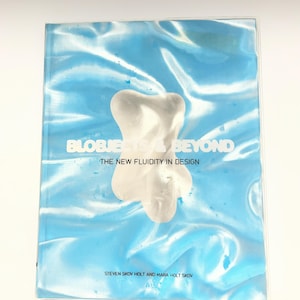May include: A book titled "BLOBJECTS & BEYOND" with the subtitle "THE NEW FLUIDITY IN DESIGN." The cover features a light blue, fluid background with a white, abstract shape in the center. The author's names, Steven Skov Holt and Mara Holt Skov, are printed at the bottom.