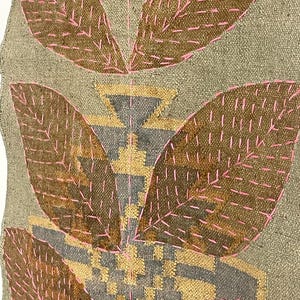 May include: Textile art with a neutral backdrop, featuring large, leaf-like forms in brown, highlighted with pink stitching. The design incorporates geometric patterns in gold and grey.