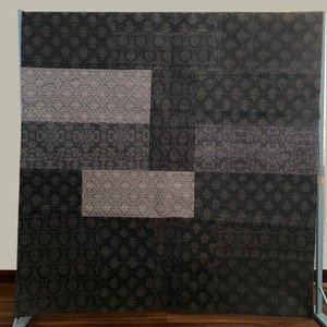 May include: A black and white patterned fabric with a patchwork design. The fabric is made up of different squares of fabric, each with a different pattern. The fabric is a good choice for upholstery, curtains, or other home decor projects.