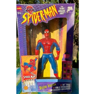 Puede incluir: Figura de acci&oacute;n de Spider-Man de la edici&oacute;n Deluxe de la serie animada. La figura roja y azul est&aacute; en una caja con un fondo de ciudad. La caja muestra el logotipo de Marvel Comics y mide 25.4 cm de alto.