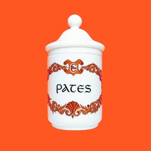 Peut inclure: Pot en céramique blanche avec un couvercle et un décor floral orange et brun. Le pot porte l'inscription "PATES" en lettres noires.