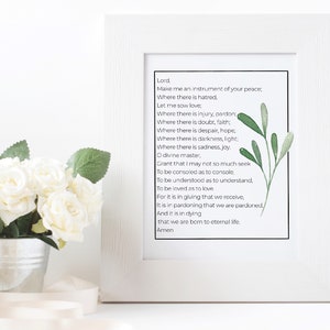 May include: A white framed print featuring a green leafy design and a poem about peace, pardon, faith, hope, light, joy, and eternal life. The poem begins with "Lord, Make me an instrument of your peace..." and ends with "...that we are born to eternal life. Amen."