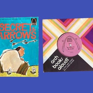 May include: Two vintage children's items: a book titled "The Secret of the Arrows" and a record with the same title. The book cover is blue with illustrations. The record has a pink label and a colorful geometric design.