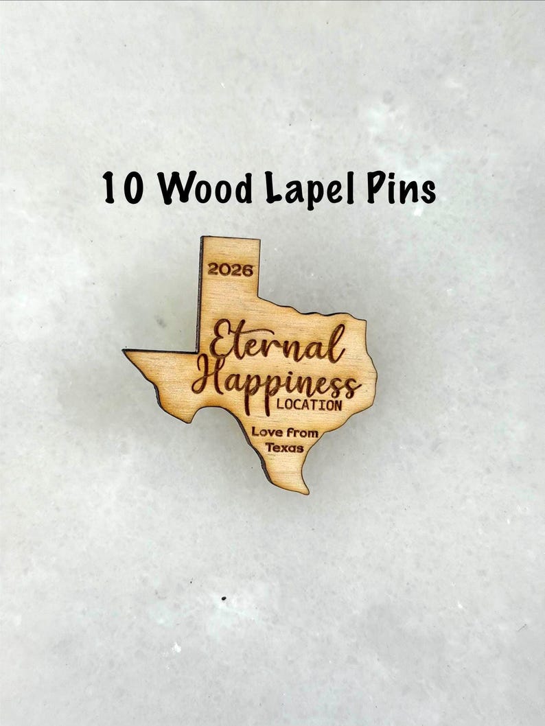 May include: Ten wood lapel pins. Each pin is shaped like the state of Texas, with the words "Eternal Happiness LOCATION" and "Love From Texas" engraved. The year "2026" is also engraved on the pin.