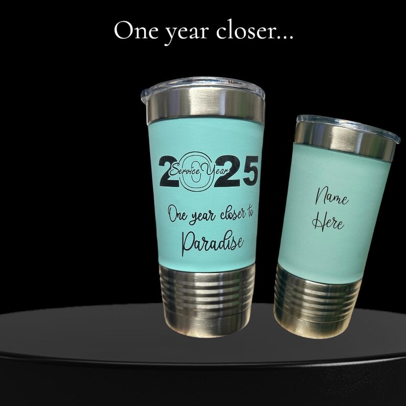 May include: Two stainless steel tumblers with a teal blue powder coating. The tumbler on the left has the text "2025 Service Year One year closer to Paradise" printed on it. The tumbler on the right has the text "Name Here" printed on it.
