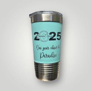 May include: A turquoise stainless steel tumbler with a black inscription that reads "2025 Service Year One year closer to Paradise".