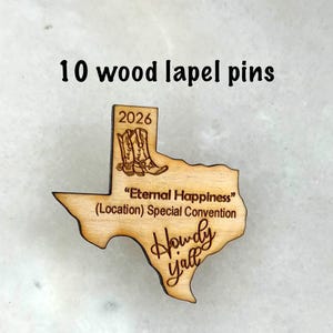 May include: Ten wooden lapel pins in the shape of the state of Texas. The pins are engraved with the text "2026", cowboy boots, and "Howdy Y'all". The pins also include the text "Eternal Happiness (Location) Special Convention".