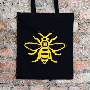 Schwarze Einkaufstasche mit den Bienen • Shopper aus 100% Baumwolle mit Bienen-Design • Mancunian Geschenk • Nördliches Pride Accessoire • Hergestellt in Großbritannien